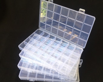 May include: A set of three clear plastic storage boxes with multiple compartments. The boxes are stacked on top of each other, with the top box open.