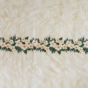 May include: A white fabric with a pattern of white palm leaves on a beige background. A border of white flowers with green leaves runs along the bottom edge.