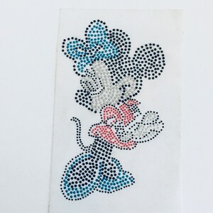 May include: A rhinestone iron-on patch featuring a cartoon mouse with a blue hat and red bow tie. The mouse is made of black, white, blue, and red rhinestones.