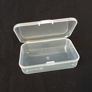 Puede incluir: Una caja de almacenamiento de pl&aacute;stico transparente con una tapa con bisagras. La caja est&aacute; vac&iacute;a y tiene una etiqueta en la parte inferior que dice "EKB-802".
