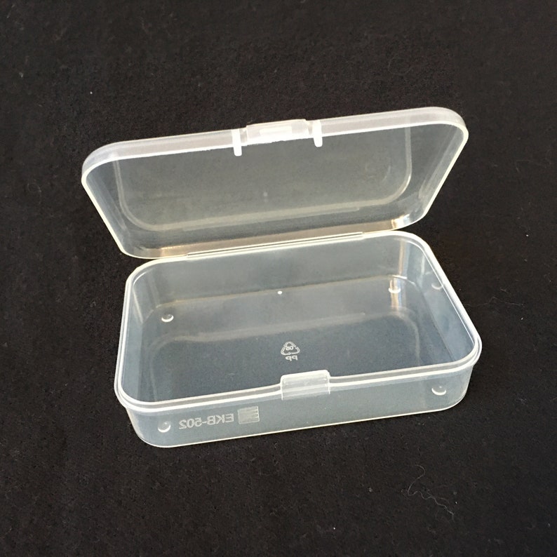 Puede incluir: Una caja de almacenamiento de pl&aacute;stico transparente con una tapa con bisagras. La caja est&aacute; vac&iacute;a y tiene una etiqueta en la parte inferior que dice "EKB-802".