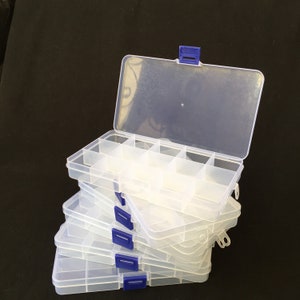 May include: A stack of clear plastic storage boxes with blue latches. The boxes are divided into multiple compartments.