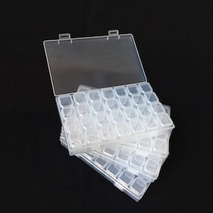 May include: A clear plastic storage box with multiple compartments. The box is stacked on top of other similar boxes. The lid is open and the box is empty.