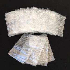 May include: A stack of clear bubble wrap sheets, commonly used for packaging and protecting fragile items during shipping.