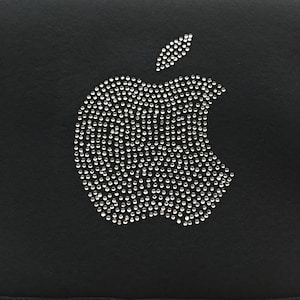 May include: A black fabric background with a silver rhinestone apple logo.