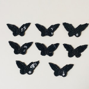 May include: Eight black sequined butterfly appliques. Each applique is about 2 inches wide and 1.5 inches tall.