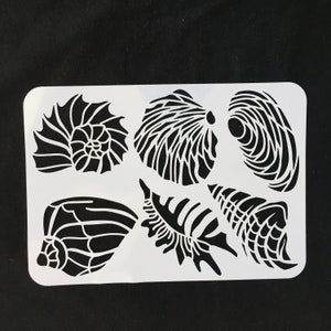 May include: A white plastic stencil with six different seashell designs. The stencil is perfect for crafting and DIY projects.
