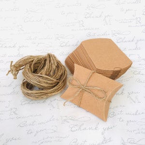 May include: A stack of brown pillow boxes with a single box tied with twine. The boxes are on a white background with the words "Best wishes to you" and "Thank you" written in cursive.