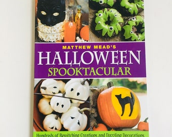 May include: A book titled "Matthew Mead's Halloween Spooktacular" with a purple cover and a variety of Halloween-themed images. The cover features a black cat, green and white donuts, pumpkins, and ghosts.