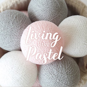 May include: A collection of spherical string balls in shades of light pink, white, and gray. The central light pink ball features the white text "living Etsy Pastel" overlaid on its surface. The balls are arranged in a cluster, showing texture.