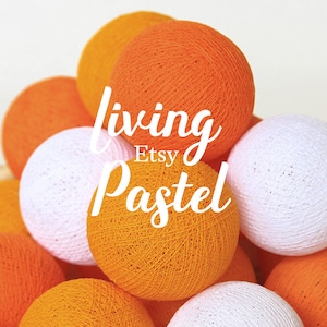 Puede incluir: Un grupo de luces de bola de algodón naranja y blanca. Las luces están dispuestas en forma de pirámide. El texto "living Pastel Etsy" está superpuesto a la imagen.