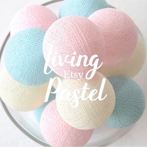 Pode incluir: Uma tigela de luzes de bola de algodão em cores pastel rosa, azul e creme. O texto "Living Pastel Etsy" está sobreposto na imagem.
