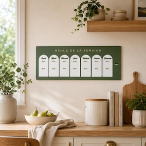 May include: A rectangular dark green wall-mounted weekly meal planner board with the text "MENUS DE LA SEMAINE" in gold lettering. It features seven white arched columns labelled with the days of the week in French, each with two sliding tabs.