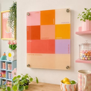 Peut inclure: Un calendrier mural rectangulaire en acrylique composé d'une grille de carrés translucides colorés dans des tons rose, orange, jaune et lavande. Le tableau affiche les jours de la semaine, notes et liste de courses, fixé par quatre entretoises.
