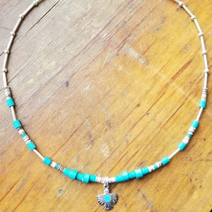 May include: A silver necklace with turquoise beads and a silver pendant shaped like a bird. The pendant has a turquoise stone in the centre.