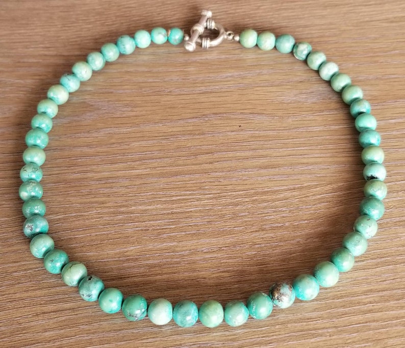 May include: A turquoise beaded necklace with a silver toggle clasp.