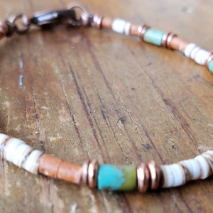 Peut inclure: Un bracelet en cuivre, turquoise et coquillages blancs avec une fermeture à fermoir.