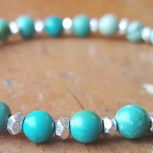 May include: A turquoise and silver beaded bracelet. The bracelet is made with round turquoise beads and silver spacer beads.