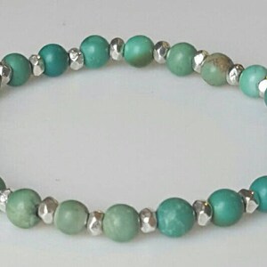 May include: A turquoise and silver beaded bracelet with graduated shades of green turquoise beads.