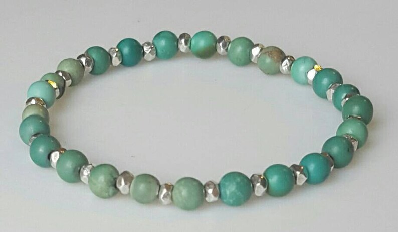 May include: A turquoise and silver beaded bracelet with graduated shades of green turquoise beads.