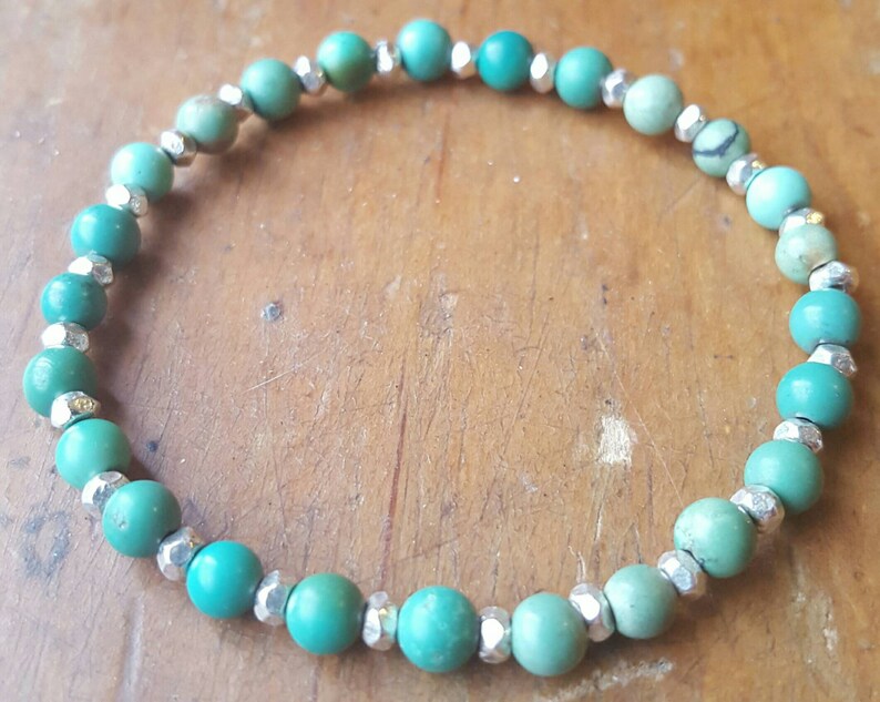 May include: A turquoise and silver beaded bracelet. The bracelet is made with round turquoise beads and silver spacer beads.