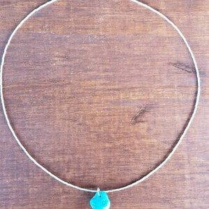 May include: A silver chain necklace with a turquoise pendant.