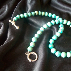 May include: A turquoise blue beaded necklace with a silver clasp and a silver toggle closure.