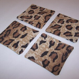 May include: Four square fabric coasters with a brown and beige leopard print design.