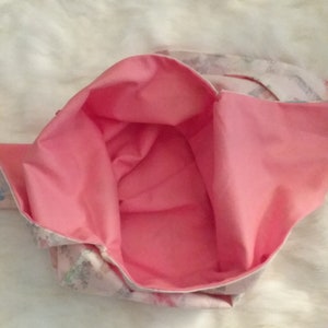May include: A pink fabric tote bag with a white floral print lining. The bag is open and the lining is visible.