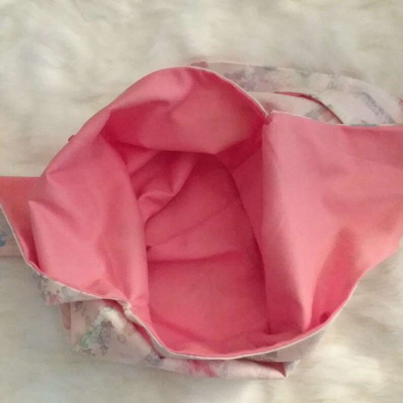 May include: A pink fabric tote bag with a white floral print lining. The bag is open and the lining is visible.