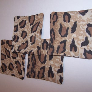 May include: Four brown and black leopard print fabric coasters. The coasters are square shaped and have a light brown background with dark brown spots.