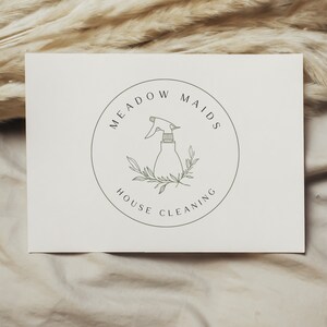 Puede incluir: Un logotipo en blanco y negro para un servicio de limpieza de casas llamado "Meadow Maids House Cleaning". El logotipo presenta una ilustraci&oacute;n estilizada de una botella de spray con hojas.