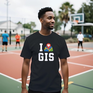 以下が含まれることがあります： 白いブロック文字で「I GIS」と書かれた黒いTシャツ。「I」は赤いハートの地図アイコンに置き換えられています。Tシャツはバスケットボールコートで着用されています。