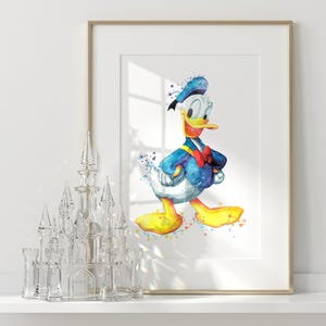 Puede incluir: Una l&aacute;mina de acuarela enmarcada de Donald Duck con camisa de marinero azul, pajarita roja y pies amarillos, expuesta junto a una figura de castillo de cristal transparente. La obra utiliza salpicaduras de pintura azul, amarilla y roja.