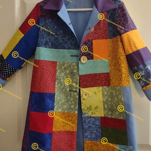 Puede incluir: Un abrigo patchwork con una variedad de cuadrados de tela coloridos. El abrigo presenta un cuello morado, forro azul claro y botones de madera. Las mangas son largas y el abrigo está colgado de una percha blanca.