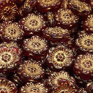 Peut inclure: Gros plan sur un tas de perles de verre en forme de fleur rouges avec des accents dorés. Les perles sont toutes de la même taille et de la même forme, et elles sont disposées de manière aléatoire.