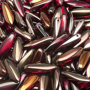 Könnte beinhalten: Ein Haufen irisierender Glasperlen in einem tiefen Burgunderrot mit goldfarbenem Schimmer. Die Perlen sind in Form von langen, schmalen Tropfen geformt.