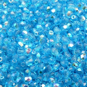 May include: A close-up of a large quantity of small, faceted, iridescent blue glass beads.