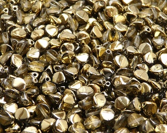 Könnte beinhalten: Nahaufnahme einer Ansammlung kleiner, goldfarbener Glasperlen. Die Perlen sind facettiert und haben eine glänzende, metallische Oberfläche.
