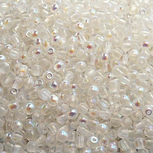 以下が含まれることがあります： 虹色の光沢のある小さな透明なガラスビーズが大量に写っているクローズアップ。ビーズは丸く、わずかに楕円形をしています。