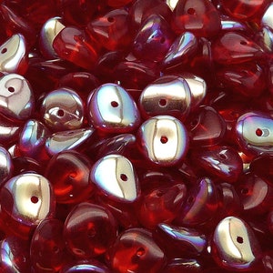 May include: A close-up of a pile of red iridescent glass beads. The beads are shaped like teardrops and have a silver sheen.