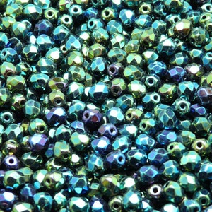 Peut inclure: Gros plan sur un tas de perles de verre facettées vert et bleu irisées. Les perles ont un éclat métallique et sont parfaites pour la fabrication de bijoux.