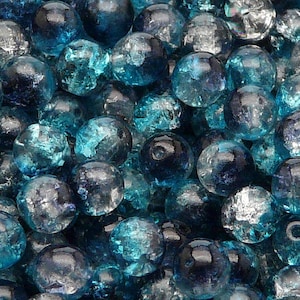 Könnte beinhalten: Nahaufnahme eines Stapels blauer Glasperlen mit einer klaren, irisierenden Oberfläche. Die Perlen sind rund und haben eine leicht strukturierte Oberfläche.