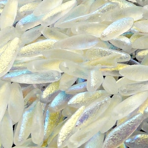 Op de afbeelding: Een stapel iriserende witte glazen kralen in een traanvorm.