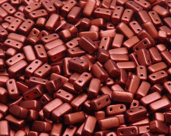 May include: A close-up view of a pile of small, rectangular, copper-colored beads with two holes in each bead. The beads have a matte finish.