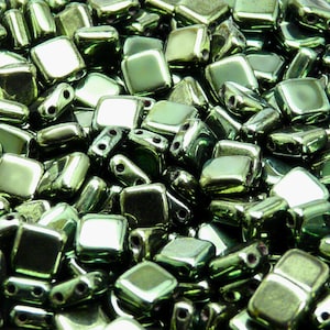 Peut inclure: Gros plan sur un tas de perles carrées en verre vert avec un éclat métallique.