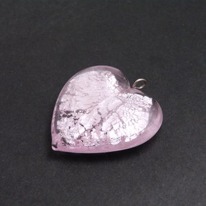 May include: A pink glass heart pendant with silver leaf accents. The pendant has a silver loop for attaching to a chain.