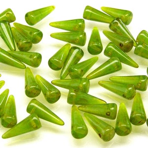 May include: A collection of green glass beads shaped like pointy cones. The beads have a translucent, slightly iridescent finish.