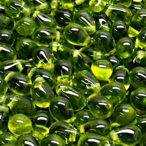 May include: A close-up of a group of lime green glass beads. The beads are pear-shaped and have a glossy finish.