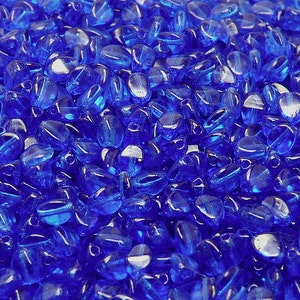 May include: A close-up view of a large quantity of small, oval-shaped, translucent blue glass beads.